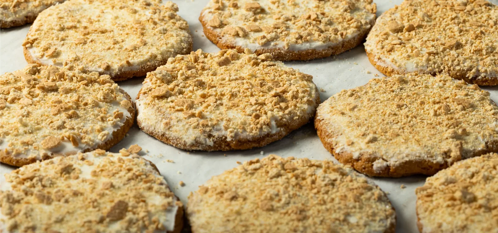 Freshly frosted crumb-topped cookies on a bakery tray